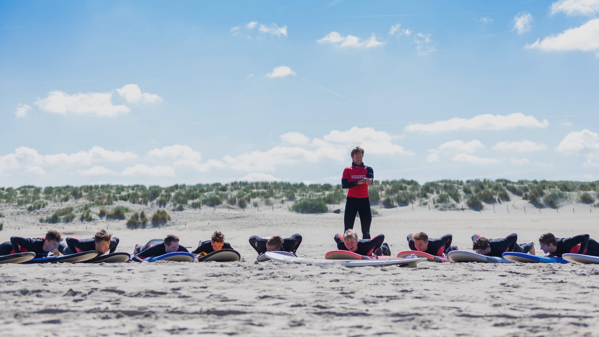 Surfles op het strand bij Monster — een instructeur begeleidt beginners in de branding